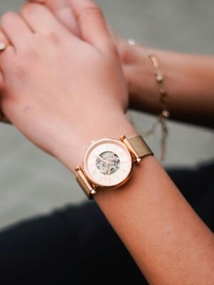 Close-up of a stylish golden wristwatch worn on a woman's wrist, showcasing elegance.