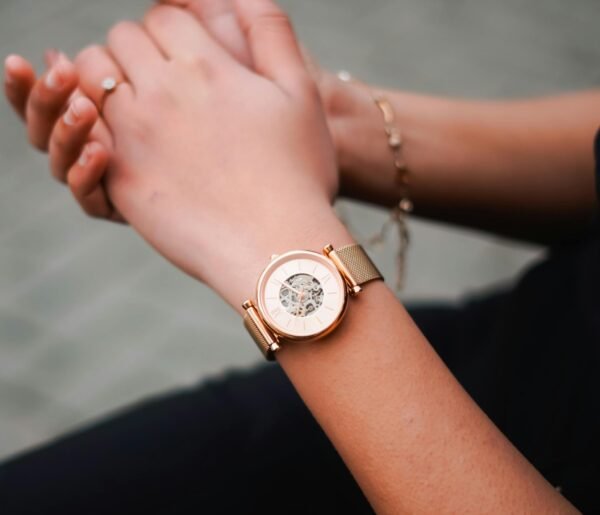 Close-up of a stylish golden wristwatch worn on a woman's wrist, showcasing elegance.