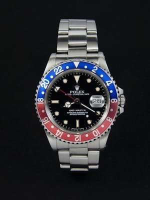 High-end stainless steel watch with dual tone bezel and date display on a dark background.